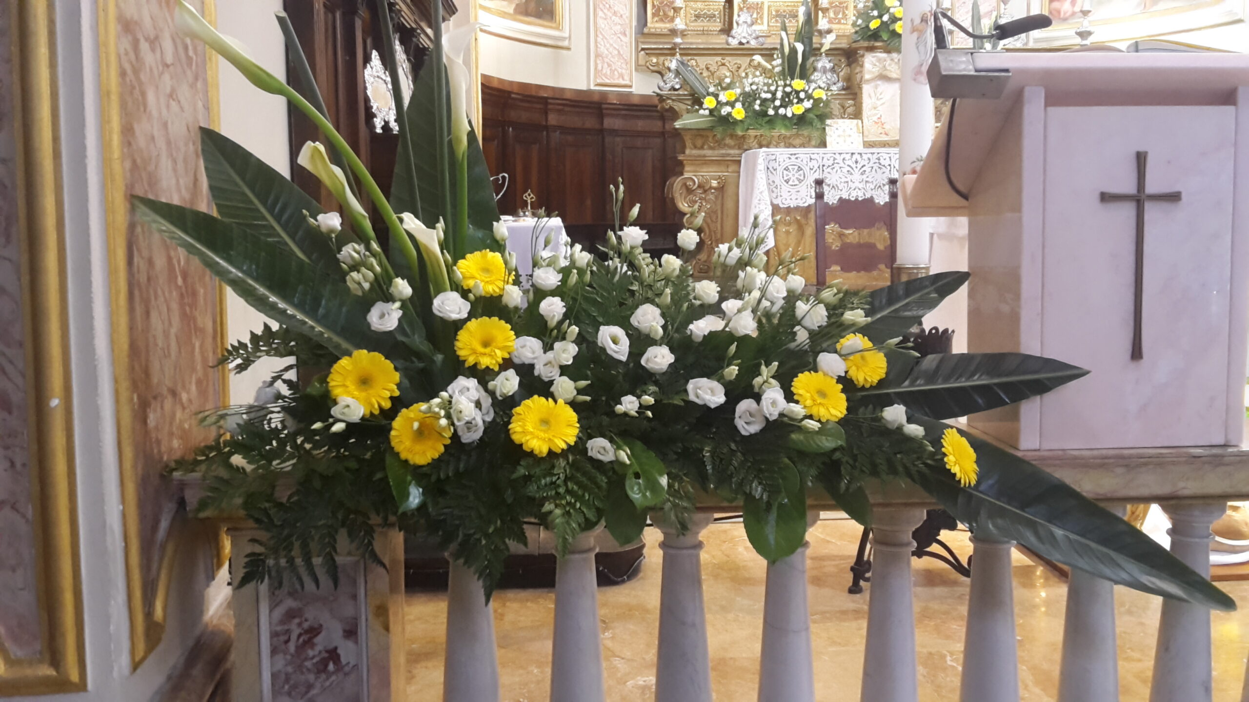 composizione floreale composta margherite bianche piccole e gerbere gialle grandi posizionata sulla balaustra di un altare