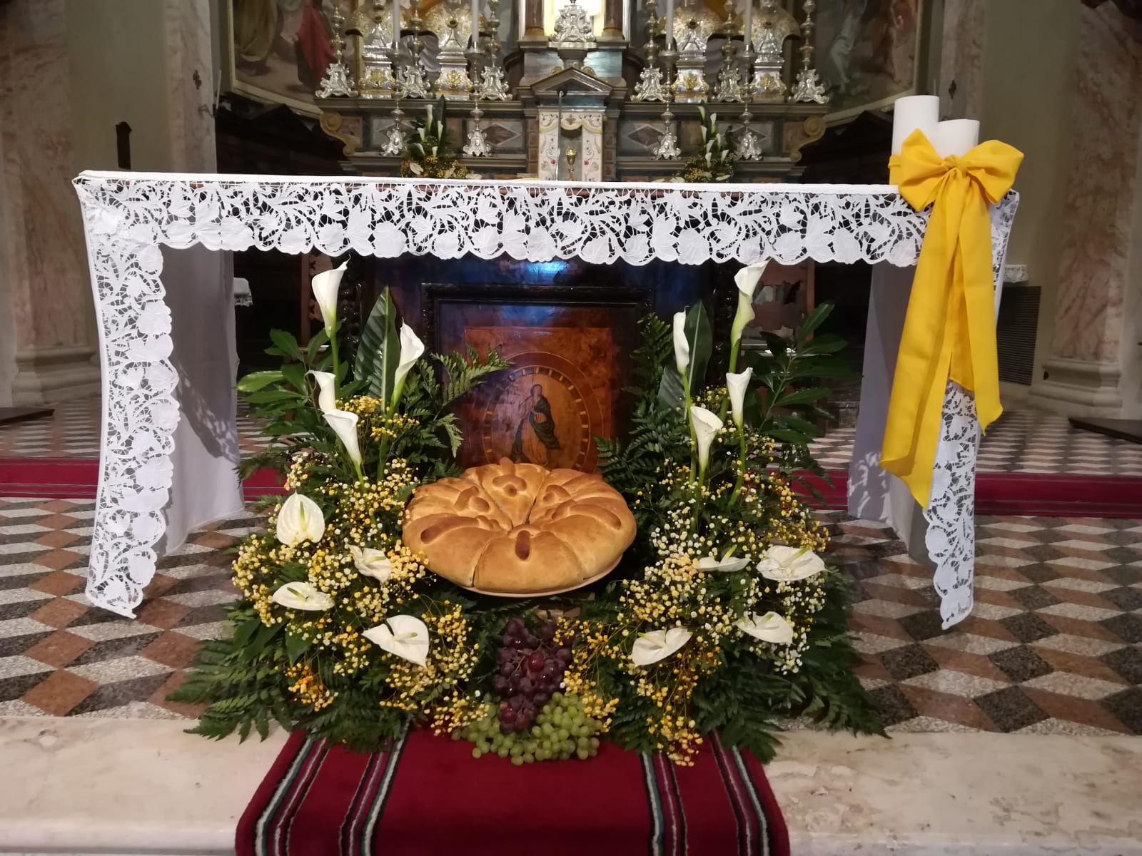 grande composizione florale di calle bianche e mimosa con pane centrale posizionato sotto l'altare per cerimonia  prima comunione