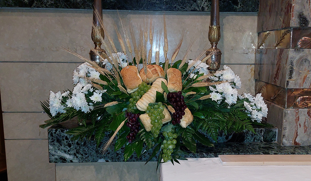 Composizione floreale composta da crisantemi, pane e uva 