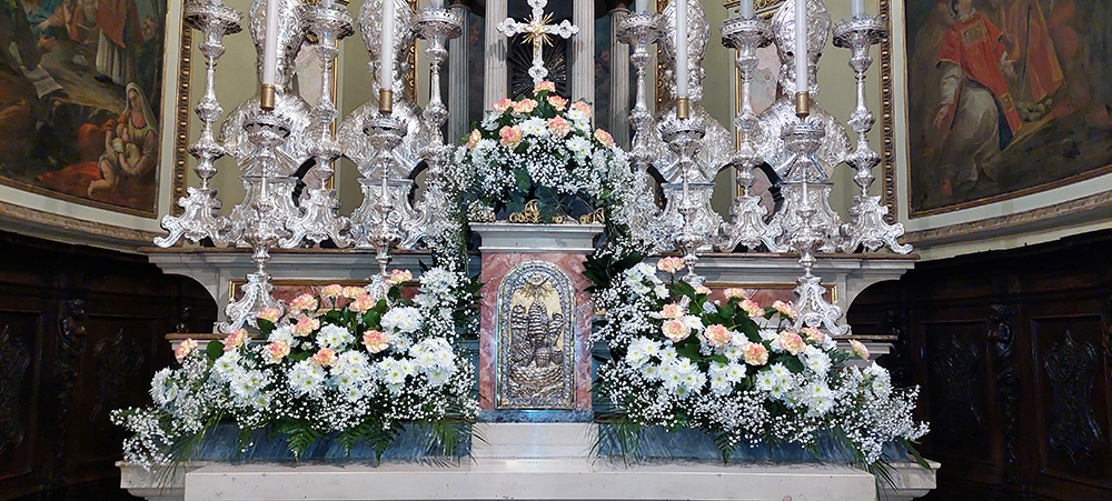 composizioni floreali che addobbano l'altare composte da garofani rosa piccole margherite bianche e velo da sposa