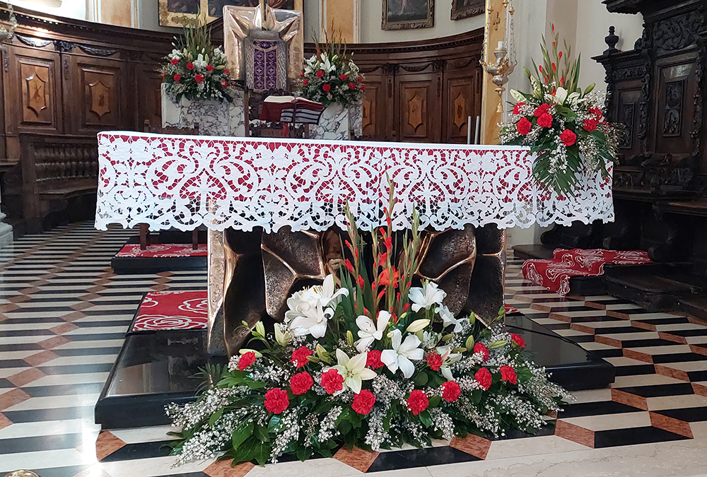 composizione florale posizionata sull'altare composta da gigli bianchi  gladioli rossi garofani rossi e velo  e velo da sposa