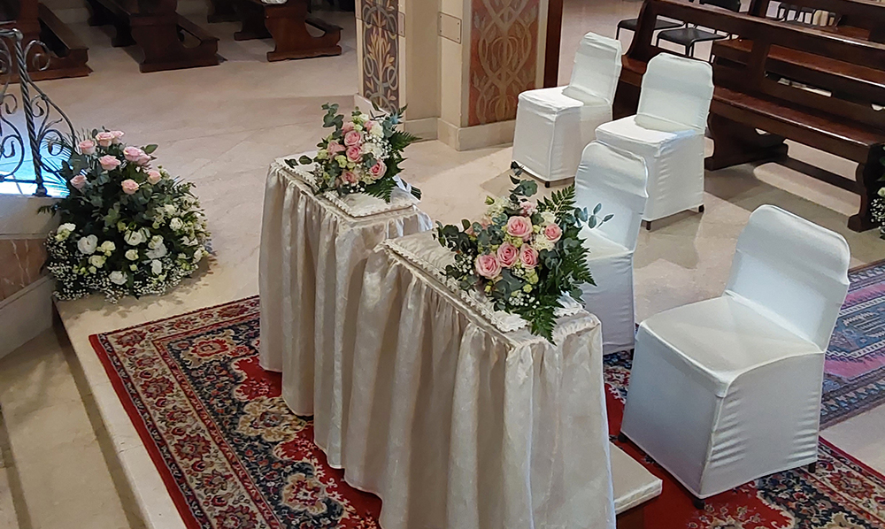 Inginocchiatoio e sedie addobbate per matrimonio con due bouquet posizionati sugli inginocchiatoi composte da rose rosa e bianche velo da sposa e felci verdi